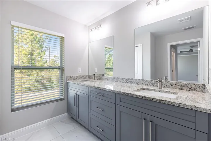 Full bathroom with double vanity and marble look tile flooring