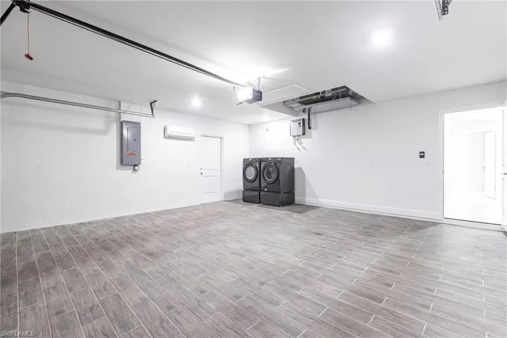 Garage featuring washing machine and dryer, electric panel, and a garage door opener