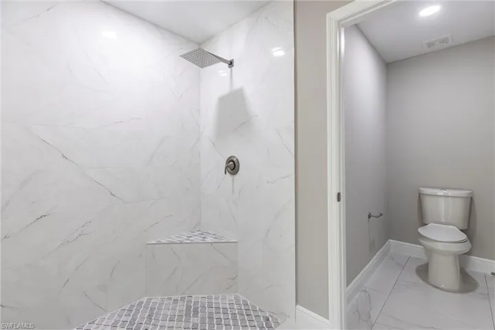Bathroom with a tile shower and marble look tile flooring