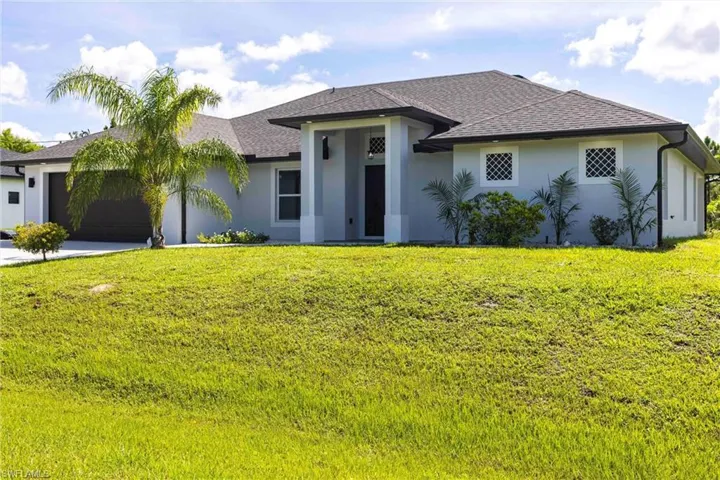View of front of property featuring stucco siding, an attached garage, roof with shingles, and a front yard