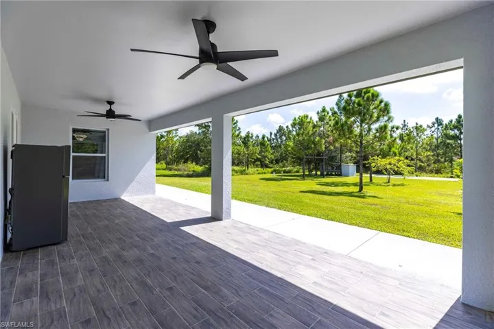View of patio featuring view of scattered trees and ceiling fan
