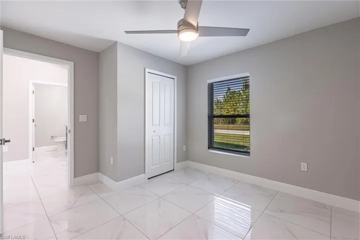 Unfurnished bedroom featuring light marble finish floors, a closet, and ceiling fan