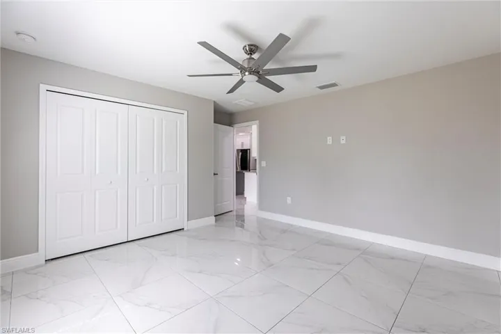 Unfurnished bedroom featuring light marble finish floors, a closet, and ceiling fan