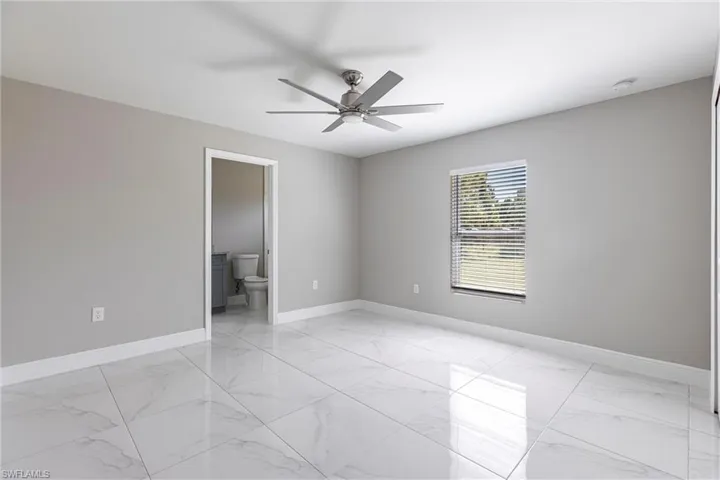 Empty room with light marble finish floors and ceiling fan