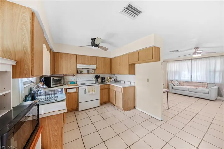 Kitchen featuring white electric range, ceiling fan, and light countertops