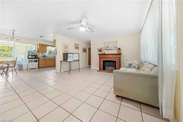 Living room featuring light tile patterned flooring, a fireplace, and ceiling fan