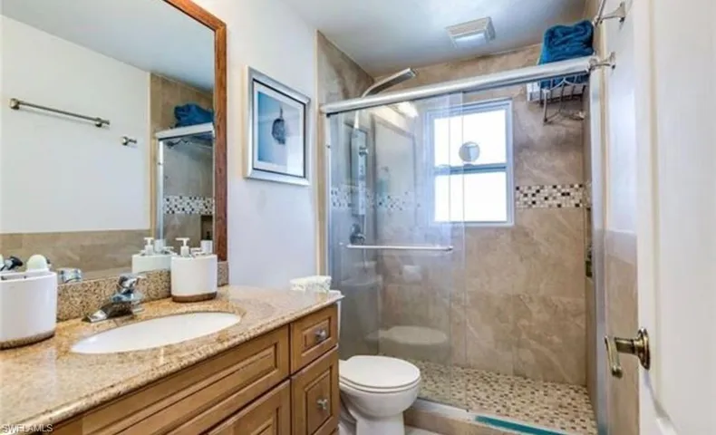 Bathroom featuring a single vanity with a granite-style countertop, wood-finish cabinetry, and a chrome faucet