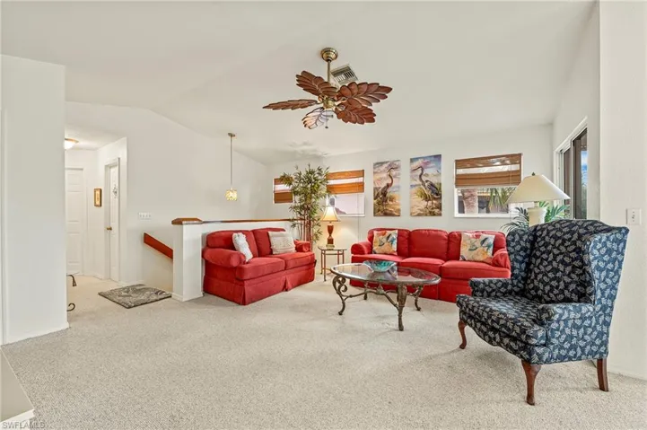 Living room featuring ceiling fan, carpet floors, and vaulted ceiling