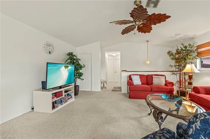 Carpeted living room with ceiling fan and lofted ceiling