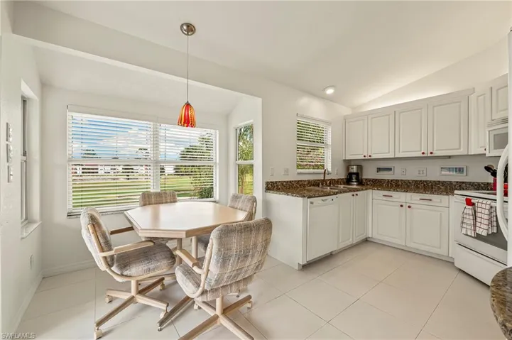 Eat in Kitchen featuring white cabinetry, white appliances, hanging light fixtures, and lofted ceiling