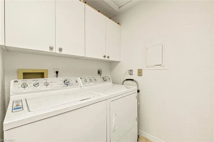 Washroom featuring cabinets, separate washer and dryer, and electric panel