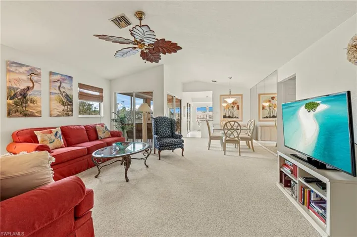 Living room with carpet flooring, ceiling fan, and lofted ceiling