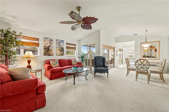 Carpeted living room with ceiling fan and lofted ceiling