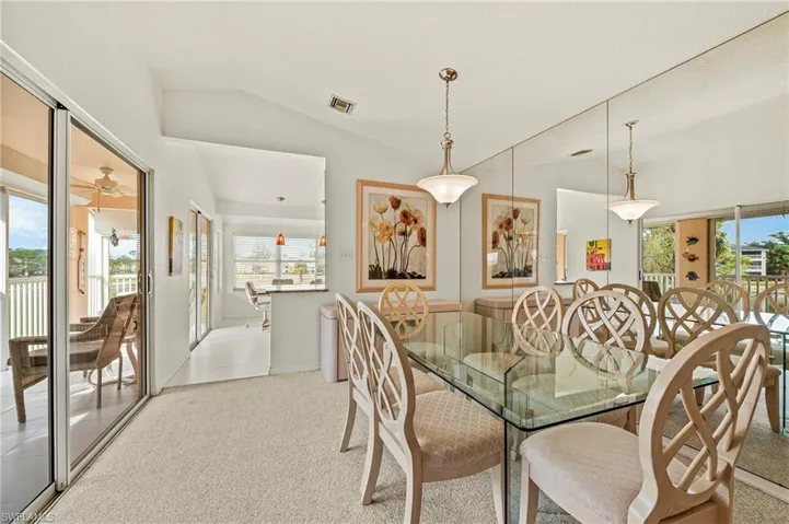 Dining space featuring a wealth of natural light, ceiling fan, light colored carpet, and vaulted ceiling