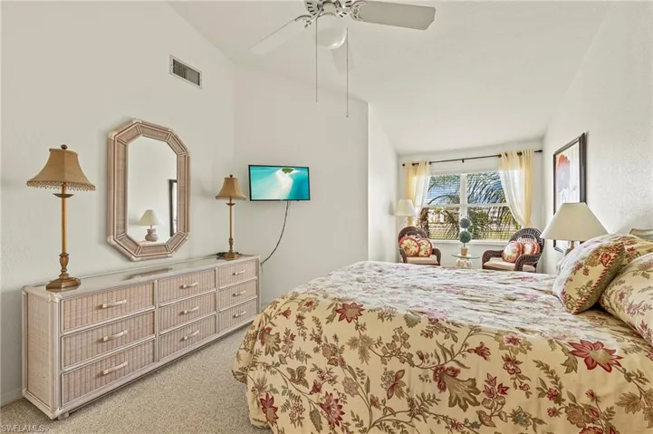 Carpeted bedroom featuring vaulted ceiling and ceiling fan