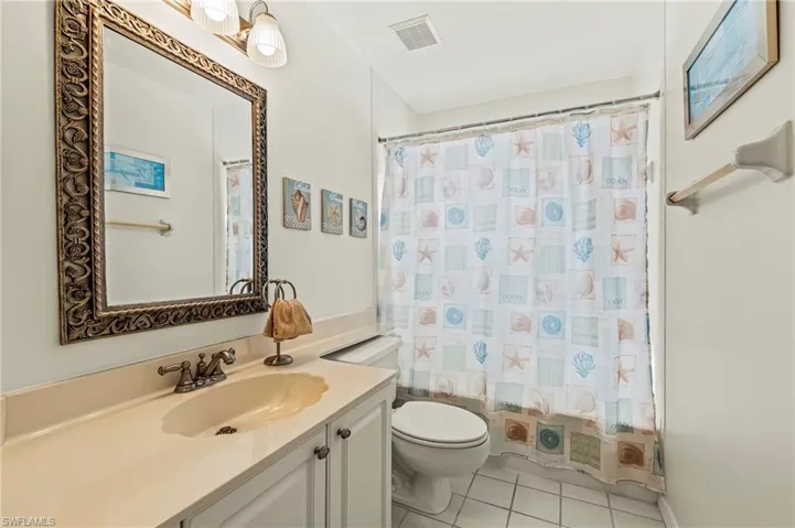 Guest bathroom with tile patterned flooring, vanity, shower / tub combo with curtain, and toilet