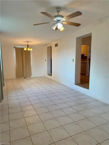 Step down family room featuring light tile patterned floors, a chandelier, and ceiling fan