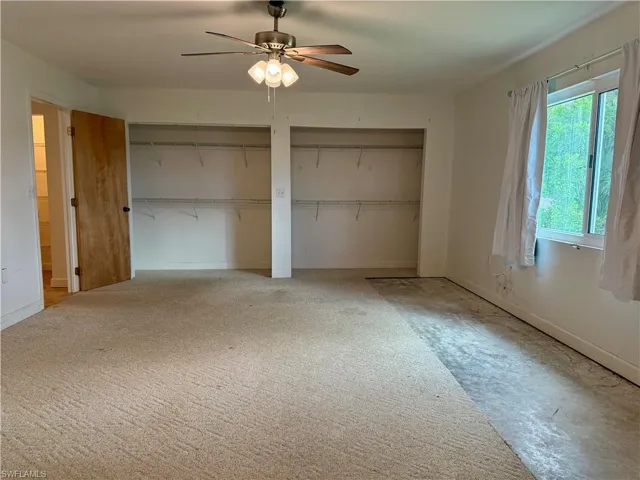 Unfurnished bedroom with ceiling fan and three closets