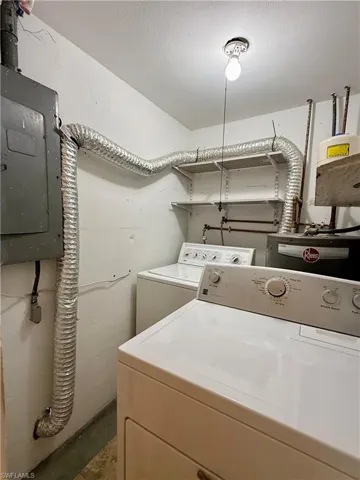 Laundry area featuring electric panel, a textured ceiling, and washing machine and dryer