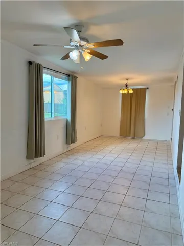Step down family room with light tile patterned floors, ceiling fan, and a chandelier