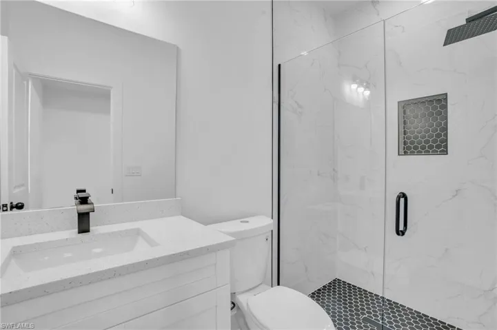 Bathroom featuring walk in shower, vanity, and toilet