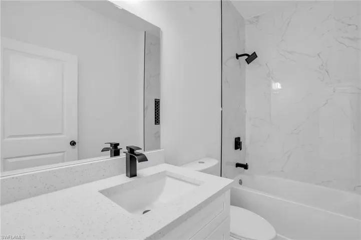 Full bathroom with vanity, tiled shower / bath combo, and toilet