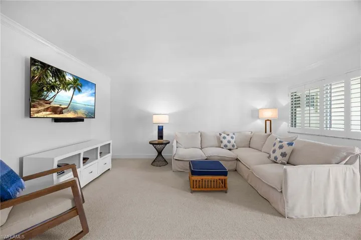 Living area with ornamental molding and light colored carpet