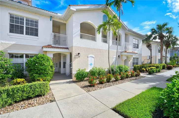 View of front of house with a tile roof, stucco siding, and a balcony