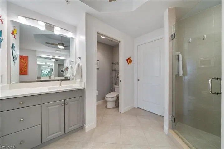 Full bath featuring a stall shower, vanity, light tile patterned floors, and ceiling fan