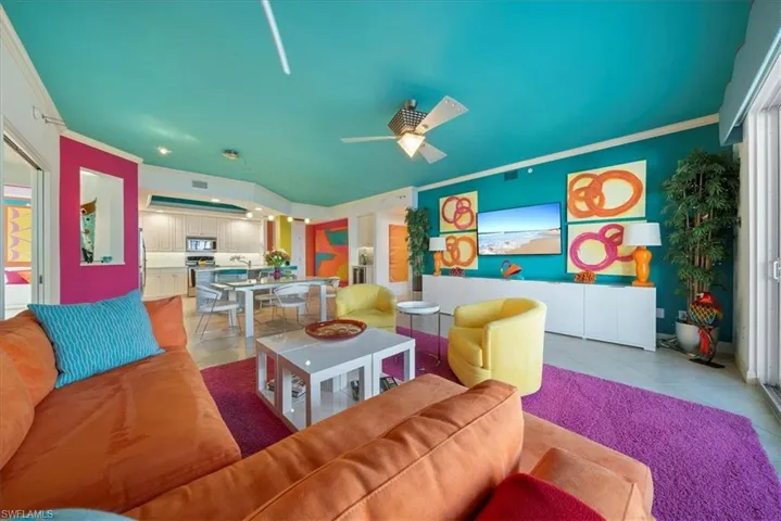 Living room featuring light tile patterned floors, ornamental molding, and ceiling fan