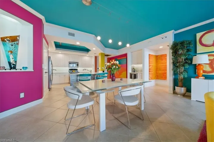 Kitchen with an island with sink, a raised ceiling, stainless steel appliances, light countertops, and light tile patterned floors
