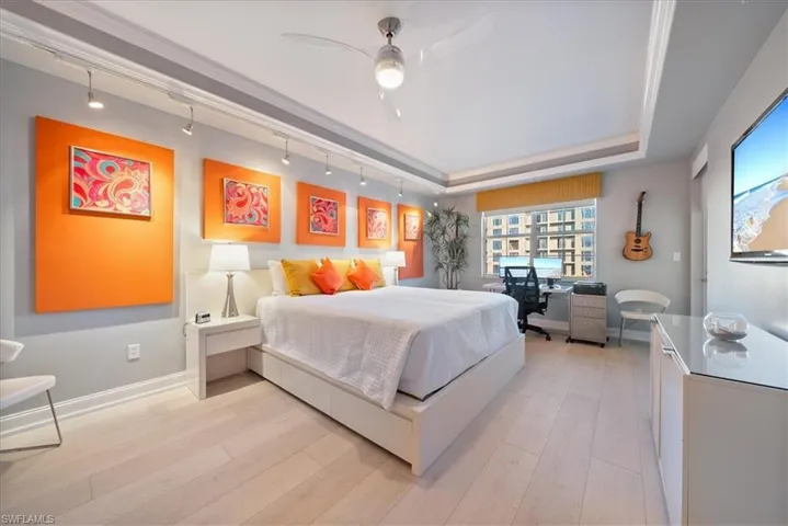 Bedroom with rail lighting, an office area, light wood finished floors, and a ceiling fan