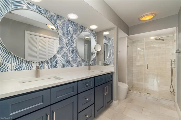 Bathroom with vanity, tile patterned floors, toilet, and a shower with door