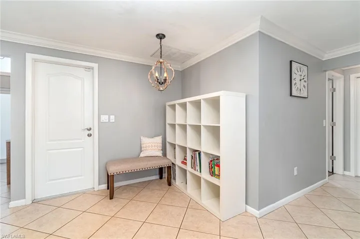 Living area featuring a notable chandelier, light tile patterned floors, and crown molding