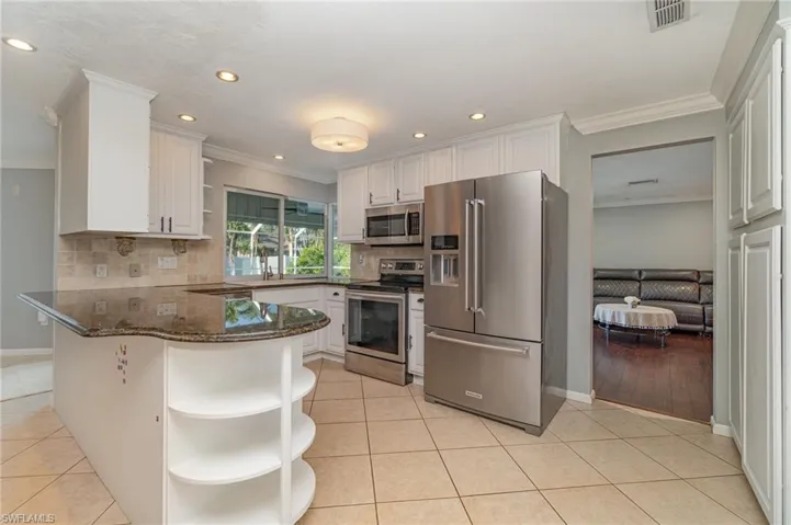 Kitchen featuring white cabinets, kitchen peninsula, stainless steel appliances, and light tile patterned floors