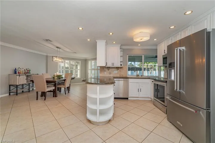 Kitchen with a wealth of natural light, white cabinetry, pendant lighting, and appliances with stainless steel finishes