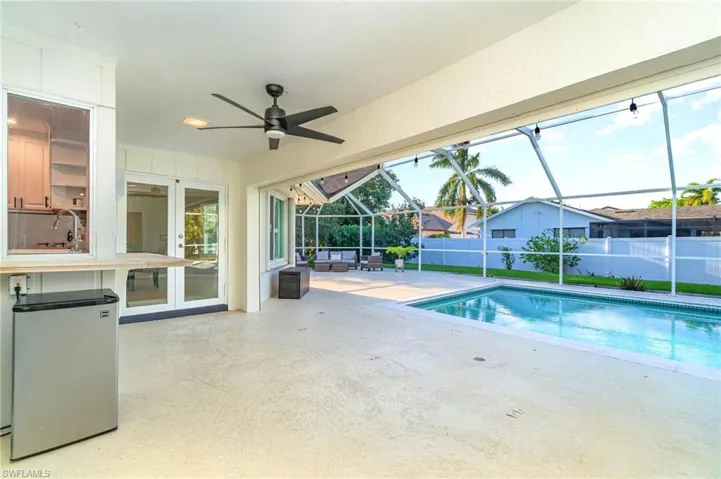 View of pool with an outdoor living space, ceiling fan, a patio area, glass enclosure, and french doors