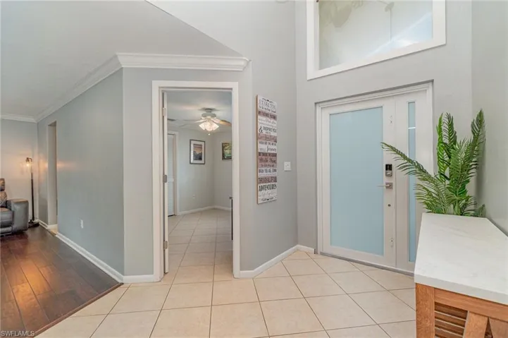 Foyer entrance with ornamental molding, light hardwood / wood-style flooring, and ceiling fan