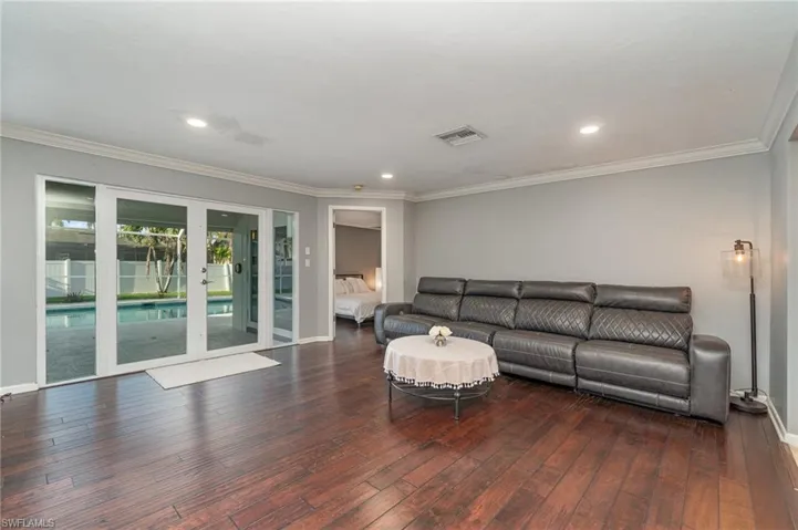 Living room with dark hardwood / wood-style flooring and crown molding