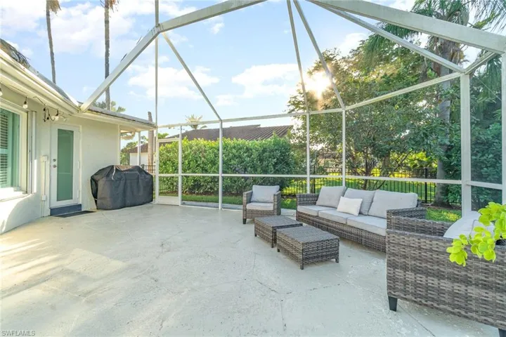 View of patio with grilling area, glass enclosure, and an outdoor hangout area
