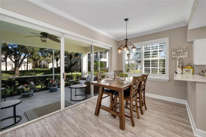 Dining area featuring ceiling fan with notable chandelier, ornamental molding, and light hardwood / wood-style flooring
