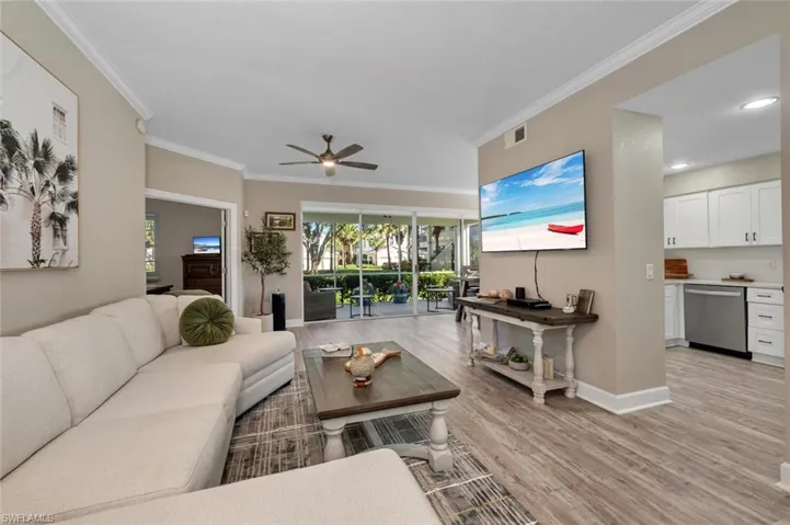 Great room with light wood-type flooring, ceiling fan, and ornamental molding
