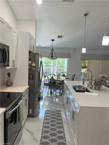 Kitchen with decorative light fixtures, stainless steel appliances, and sink