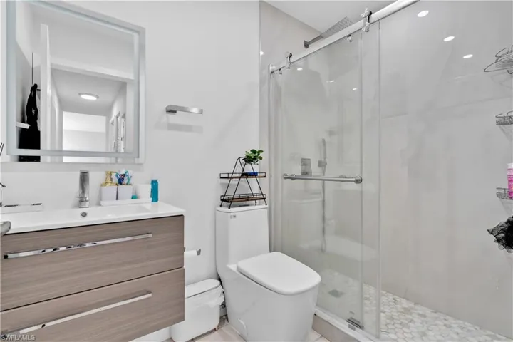 Bathroom featuring tile patterned flooring, a shower with shower door, vanity, and toilet