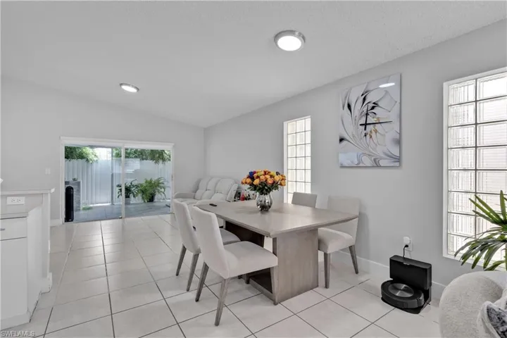 Tiled dining room featuring vaulted ceiling