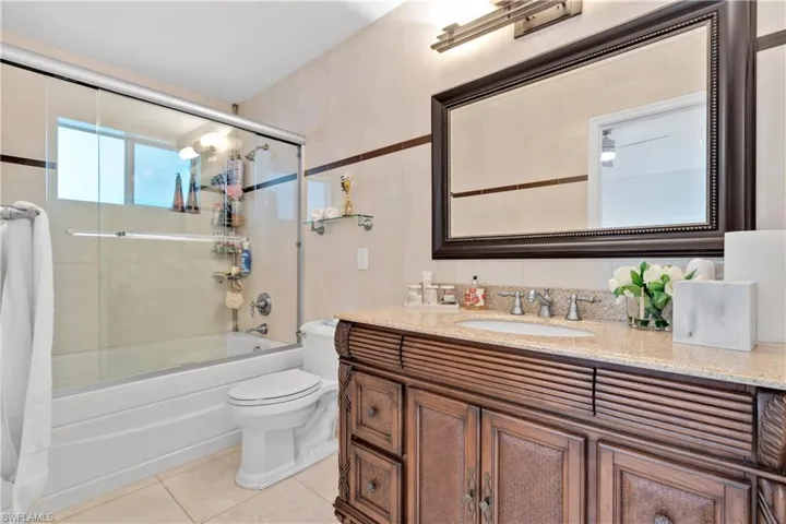 Full bathroom with tile patterned flooring, toilet, vanity, and enclosed tub / shower combo