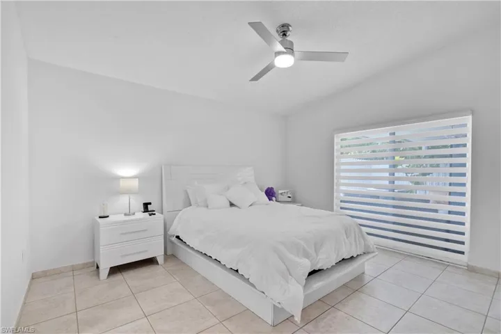 Bedroom with ceiling fan, vaulted ceiling, and light tile patterned floors