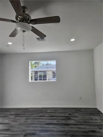 Empty room featuring recessed lighting, dark wood-style flooring, baseboards, visible vents, and a ceiling fan