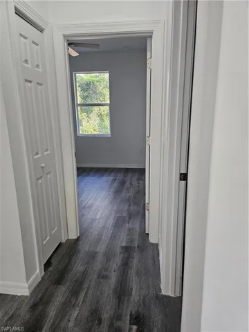 Hallway featuring dark wood-style floors and baseboards