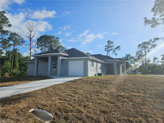View of front of house with concrete driveway, stucco siding, central air condition unit, and an attached garage